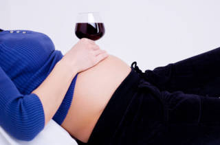 Une femme enceinte avec un verre de vin rouge