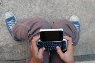 Jeune qui ecrit un sms sur son portable