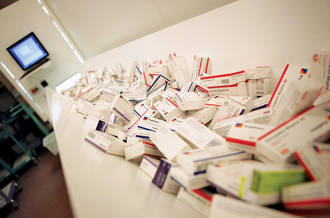 Les boîtes de médicaments en vrac avancent sur un tapis pour être scannées et rangées dans le robot