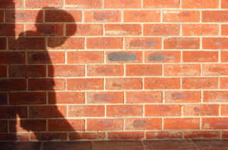 Ombre repliée devant un mur de briques